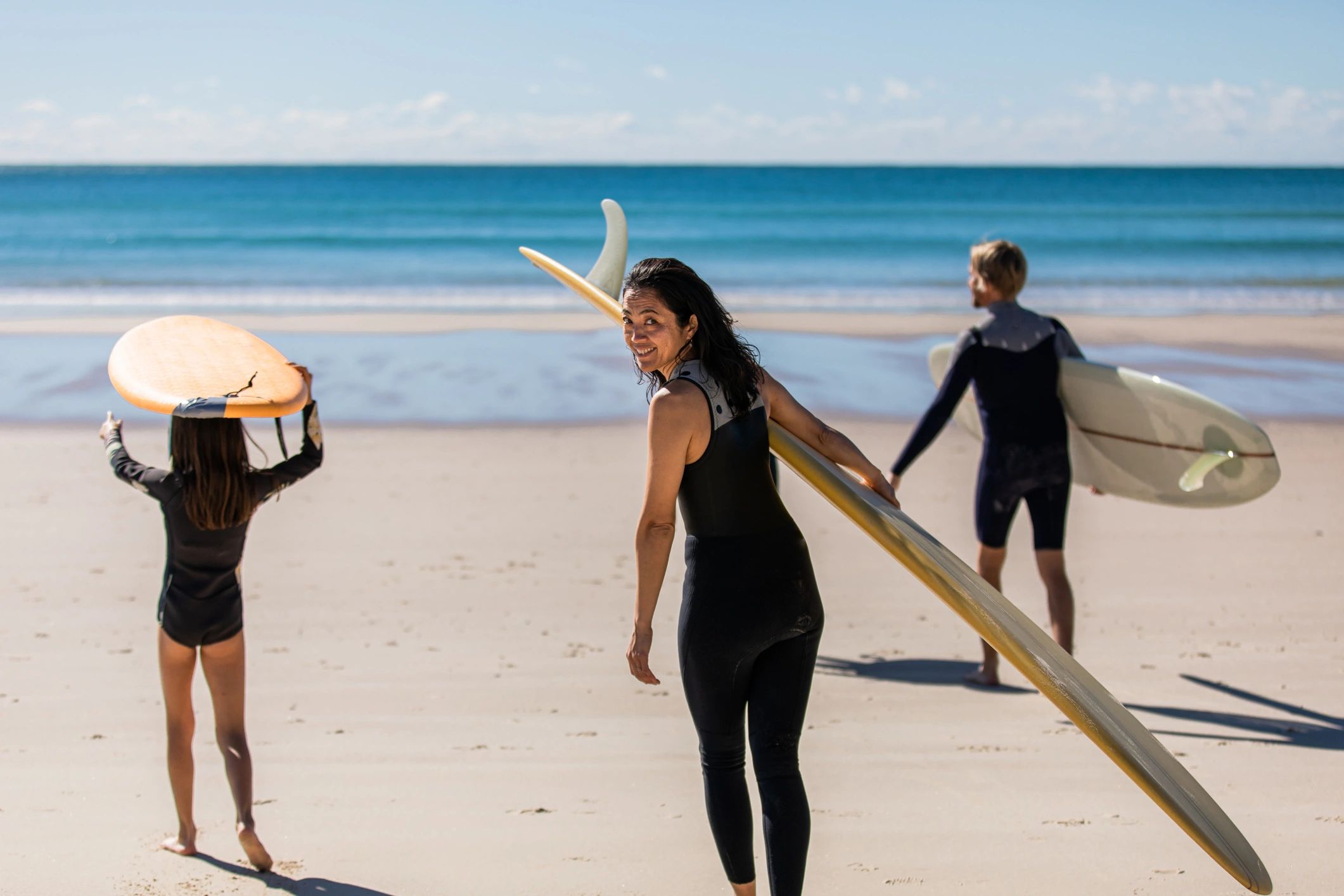 Family walking into the water with surfboards
